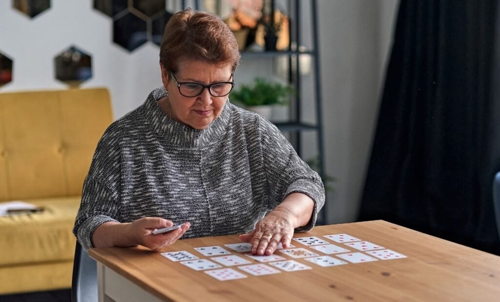 Older woman plays a card game by herself