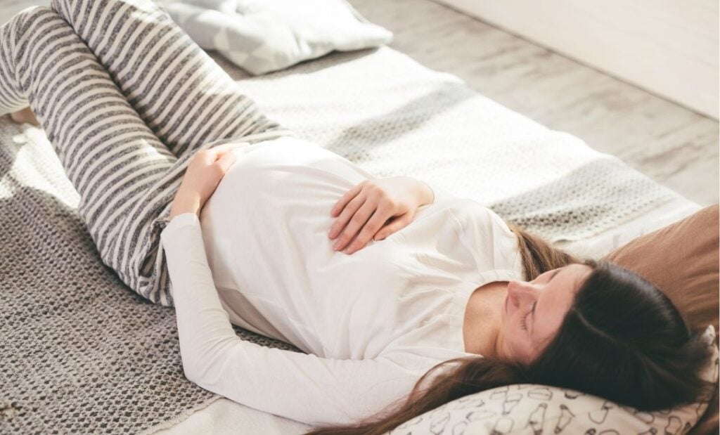 Pregnant woman lays on bed