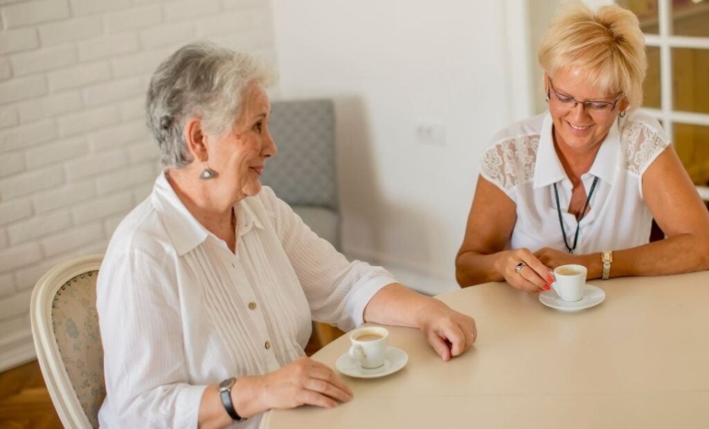 Two older women sit and have coffee together