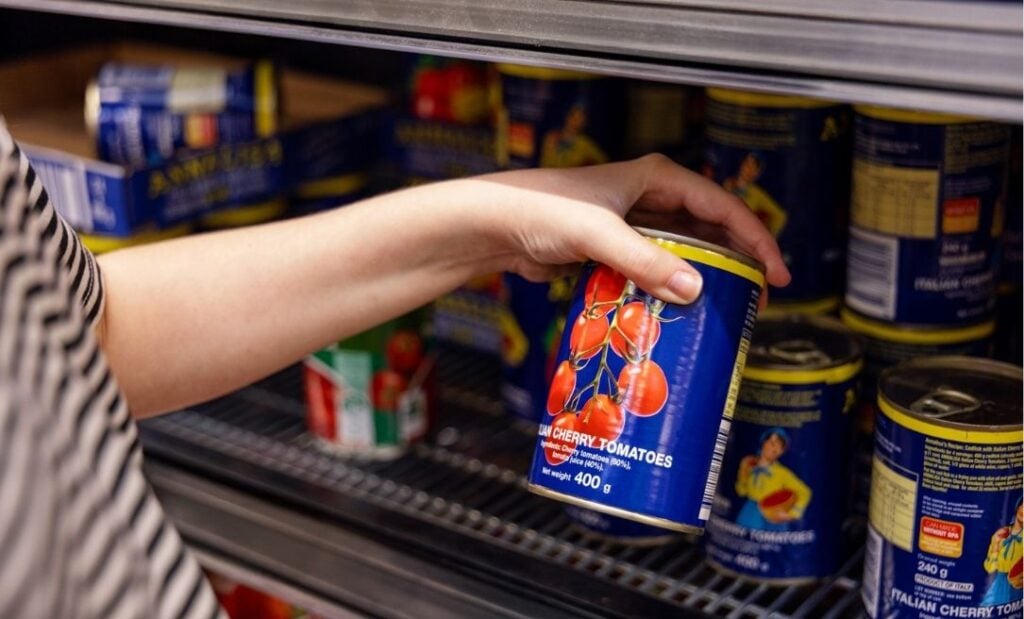 Close up on woman holding canned tomatoes in supermarket