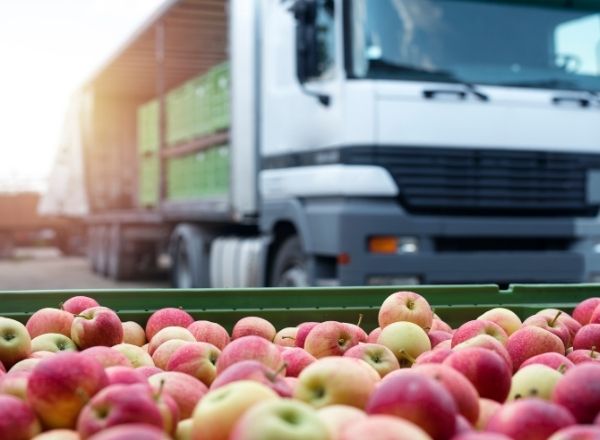 Delivery of a pallet of fresh apples with food transport truck in the background