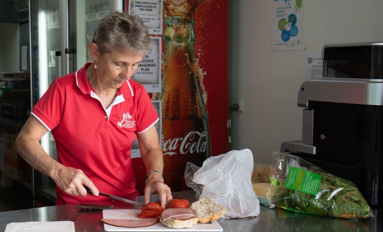 Canteen officer prepping fresh food on stainless steel canteen bench