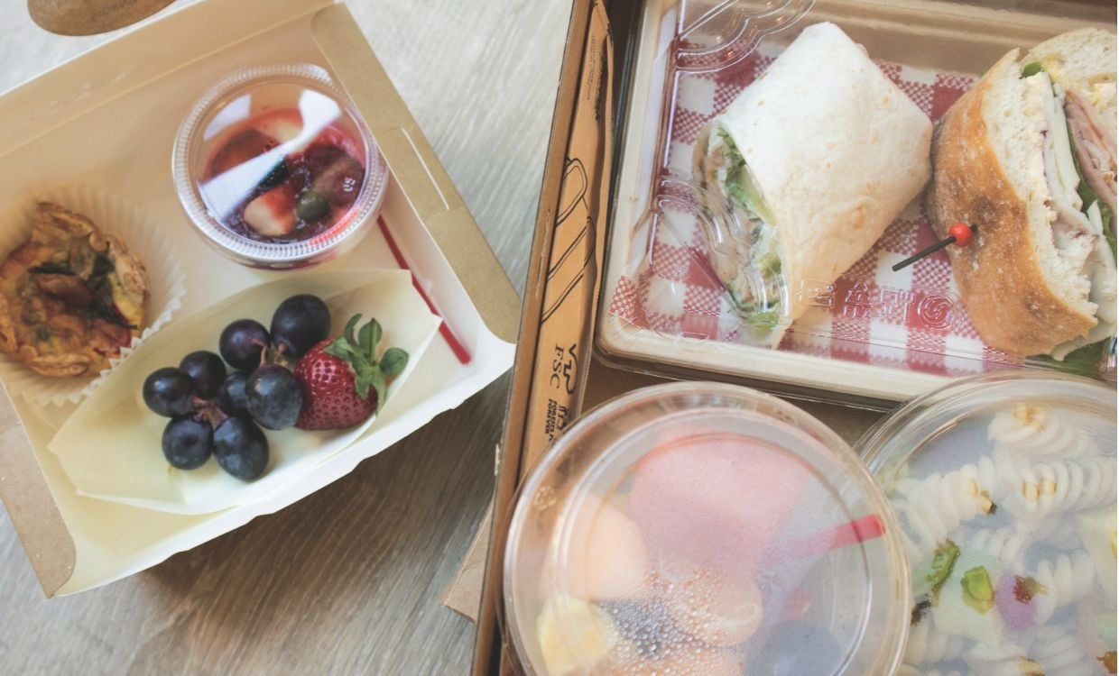 Healthy lunch and snack options in takeaway containers on a canteen table