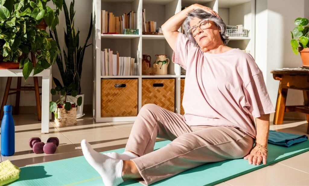 Older woman stretches on yoga mat in the sunshine
