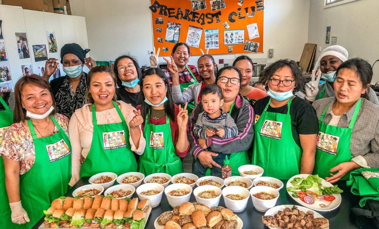 Group of participants standing around a kitchen bench displaying food they have prepared as part of the Community Champions Cultural Cooking Program