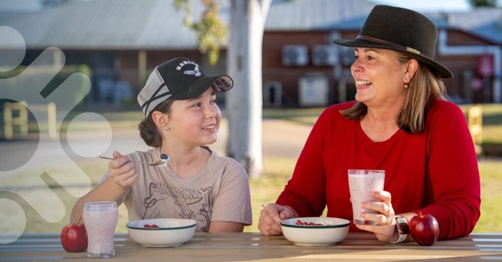 Mother and daughter enjoying a healthy breakfast together at a table in a local community park setting