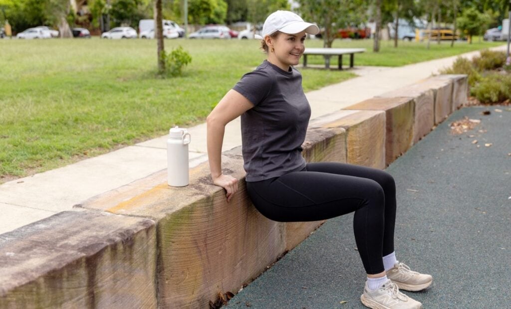 Woman does tricep dip using a retaining wall